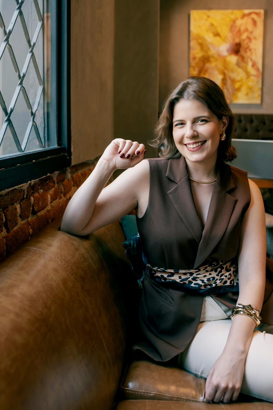Lívia Marostiga sorrindo, sentada em um sofá de couro
